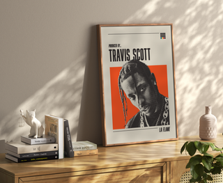 Travis Scott poster with black and white halftone imagery and orange background, framed on a wall.