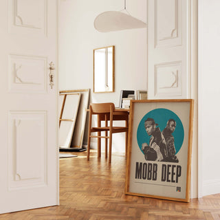 Mobb Deep poster in a frame leaning against a wall in a stylish room with wooden flooring.