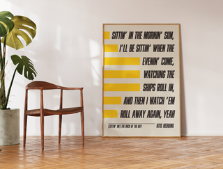 Otis Redding "Sittin' on the Dock of the Bay" lyrics poster on wooden floor.